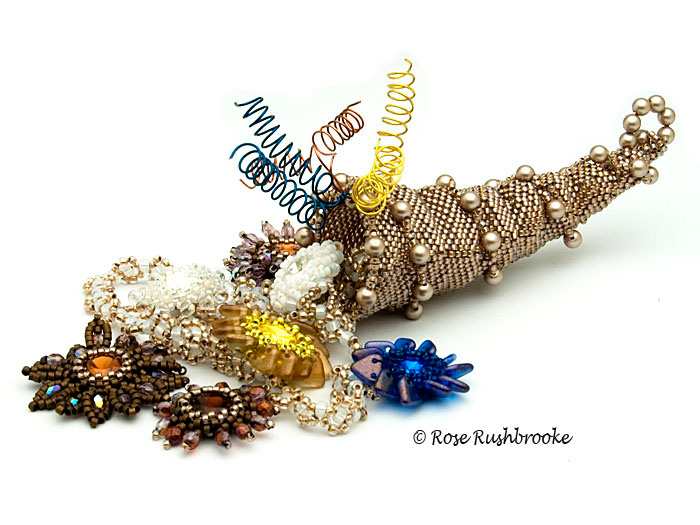 Horn of Plenty basket containing a necklace by Rose C Rushbrooke. Beadweaving - seed beads, fire polish crystals, delicas, Swarovski rivolis, and wirework. Image copyright &copy; Rose C Rushbrooke.