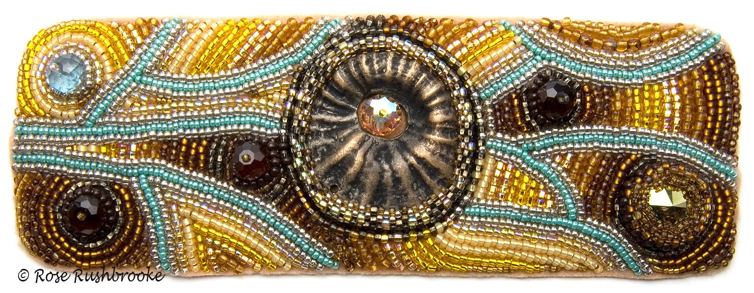 Flat version of Inspired by a Bee cuff by Rose C Rushbrooke. Bead embroidery on a copper cuff. Glass seed beads, polymer clay cabuchon, Czech glass beads, and crystals. Image copyright &copy; Rose C Rushbrooke.