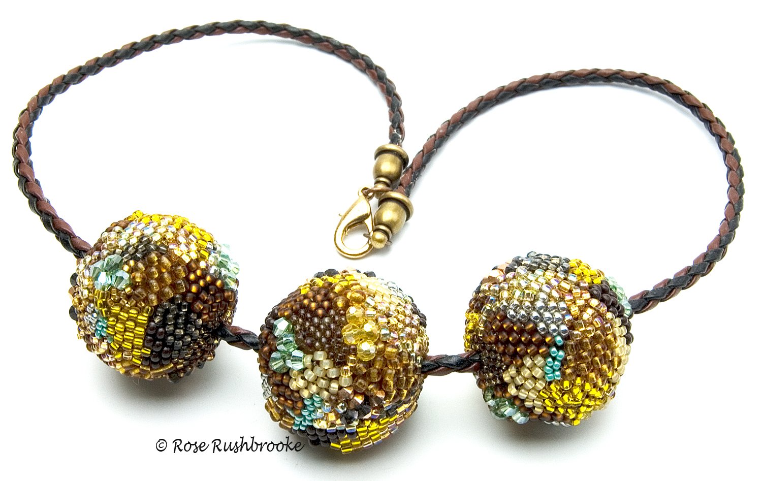 Inspired by a Bee necklace by Rose C Rushbrooke. Beadweaving over a wooden bead using glass seed beads and crystals. Strung on a braided faux leather cord. Image copyright &copy; Rose C Rushbrooke.