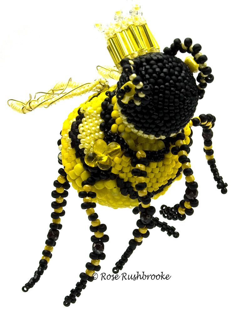 The queen bee herself. Wooden beads covered in seed beads, wire wrapped wings, and seed bead antenna and legs. Image copyright © Rose Rushbrooke.