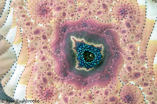 Close up of a beaded ammonite stitched onto a Mandelbrot Lake. Image copyright &copy; Rose Rushbrooke.